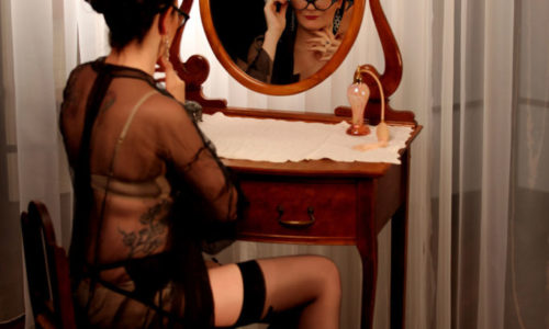 Woman adjusting glasses at a dressing table